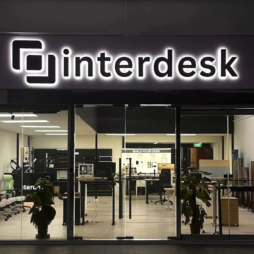 The exterior of the Interdesk showroom with illuminated branding and the store interior visible